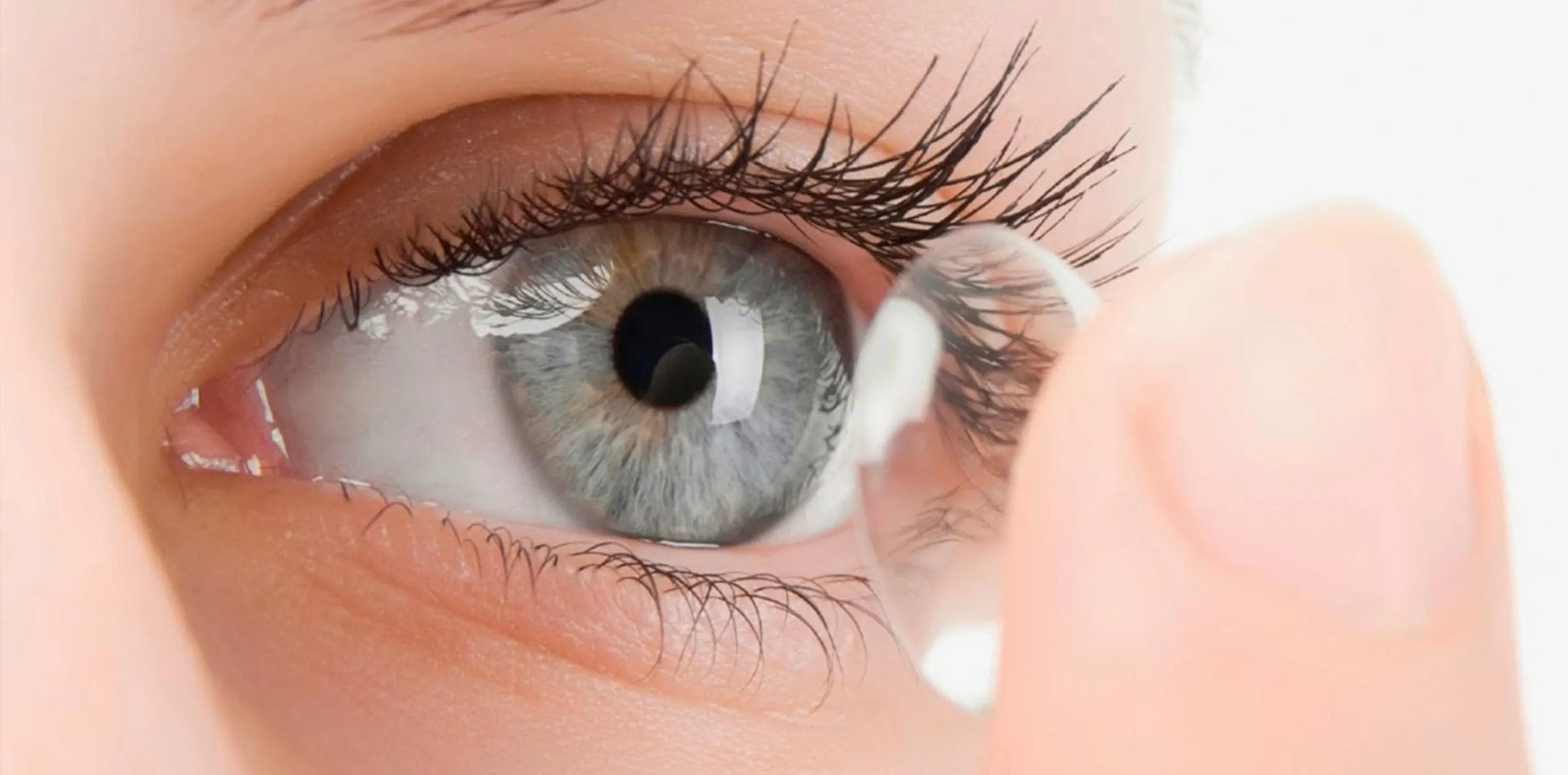 Primer plano de un ojo mientras se coloca una lente de contacto con la punta del dedo