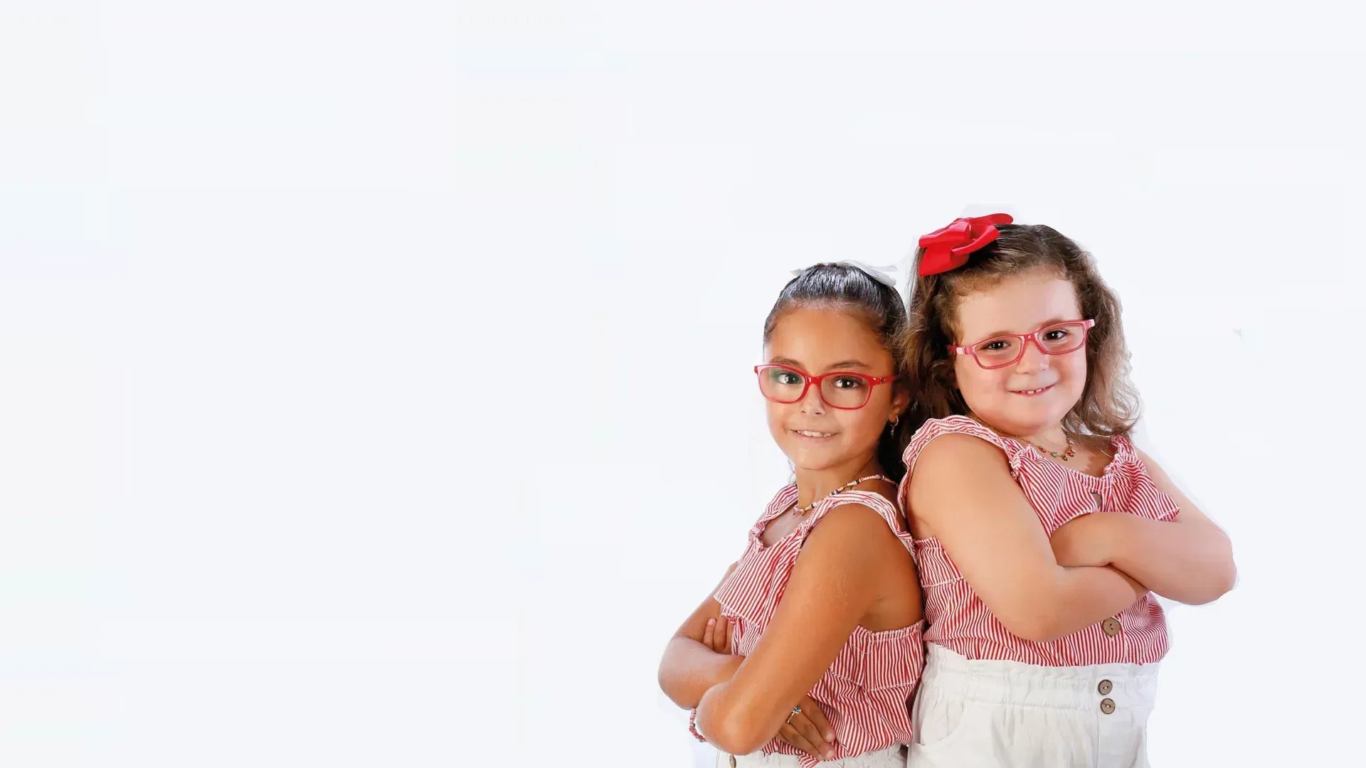 Dos niñas con gafas de colores, espalda contra espalda, sobre fondo claro